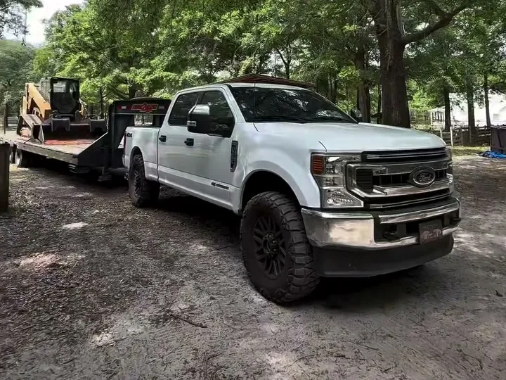 Truck and gooseneck trailer hauling equipment to a dirt work job