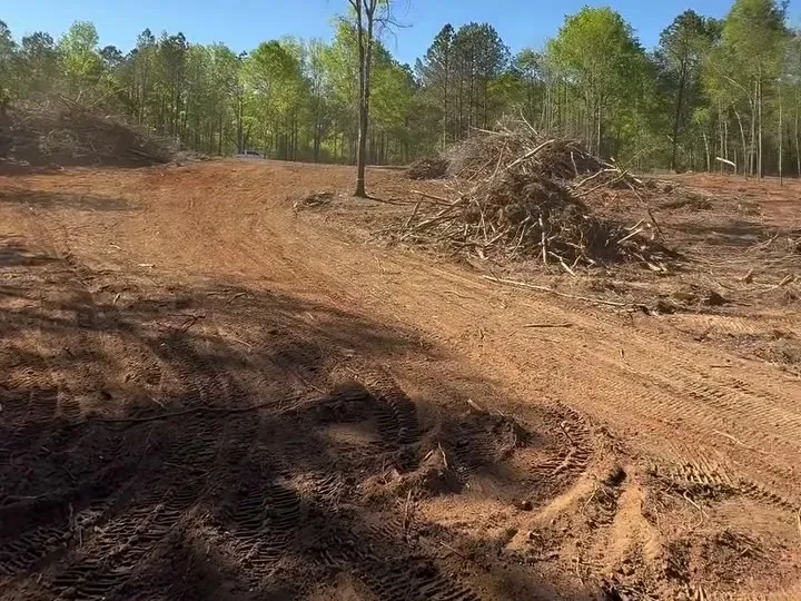 Rough graded dirt lane cut across a cleared lot before stone goes down